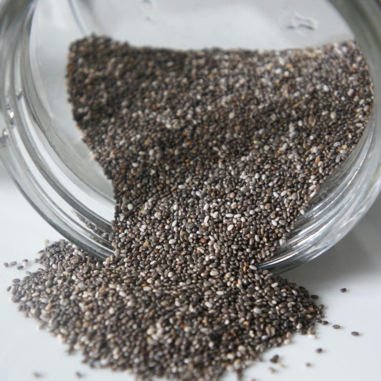 Chia seeds pouring out from a glass jar, perfect for healthy lifestyle or food blogs.